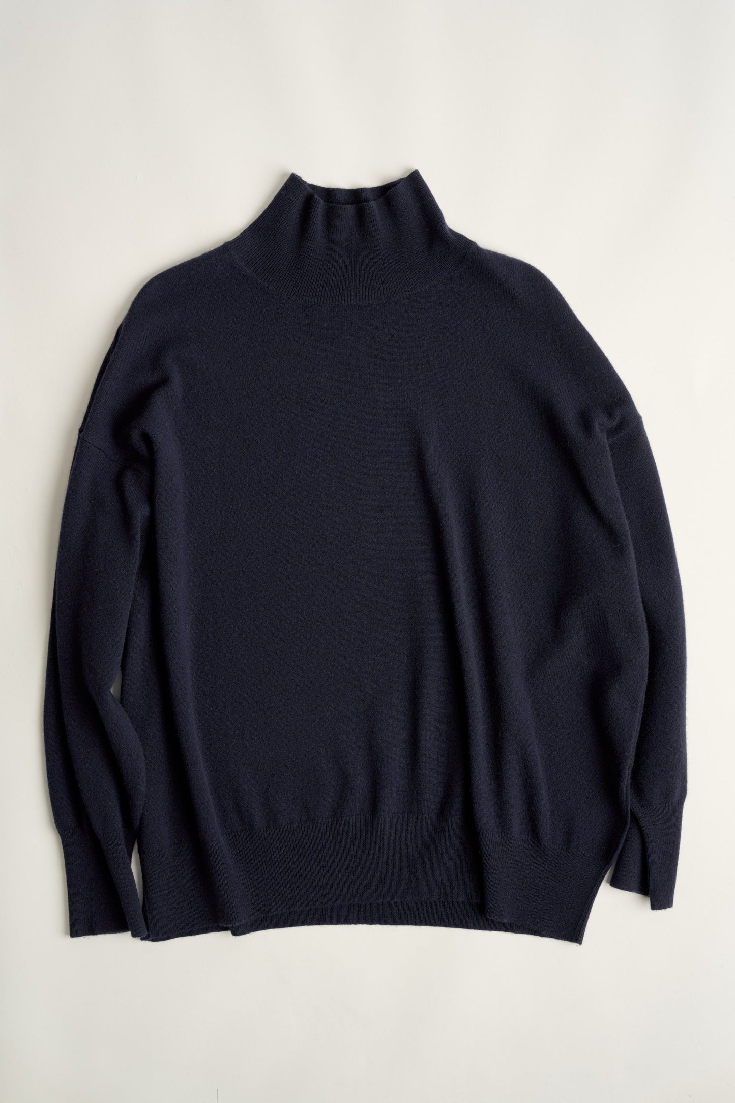 This image features the Kotto Sweater, highlighting its high-neck design and snug, comfortable fit. The sweater is presented in a classic, versatile ocean color, which enhances its elegant and timeless appeal.