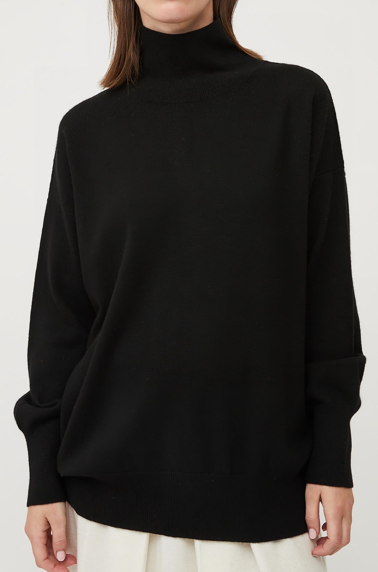 This image features the Kotto Sweater, highlighting its high-neck design and snug, comfortable fit. The sweater is presented in a classic, versatile black color, which enhances its elegant and timeless appeal.