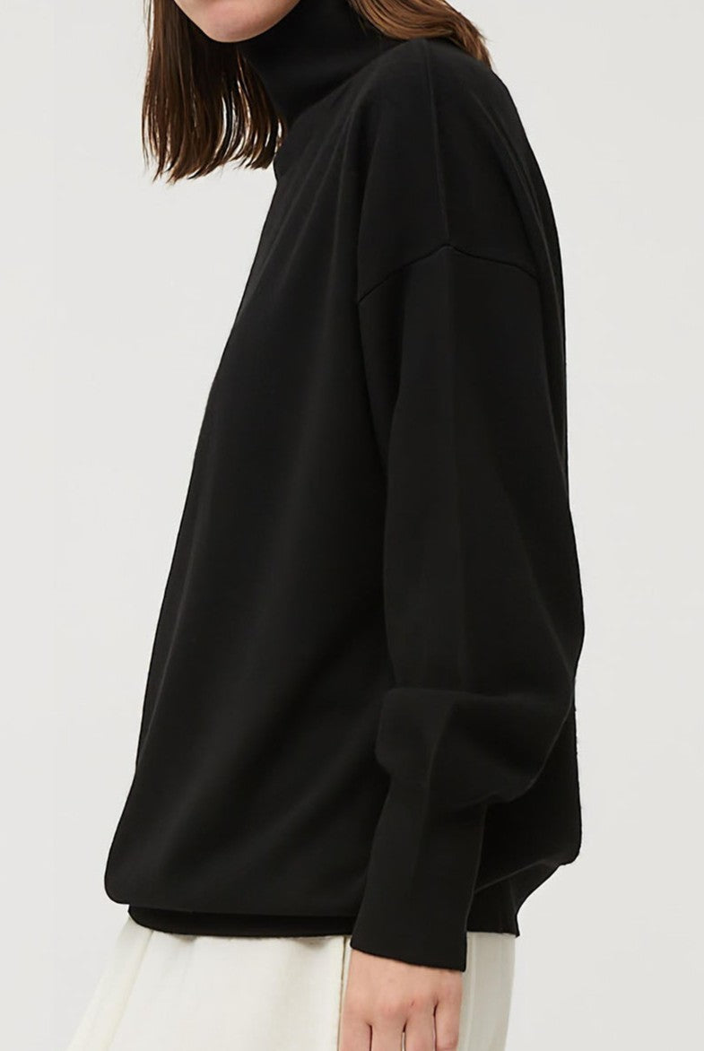 This image features the Kotto Sweater, highlighting its high-neck design and snug, comfortable fit. The sweater is presented in a classic, versatile black color, which enhances its elegant and timeless appeal.