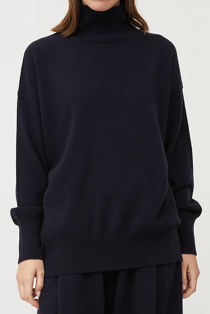 This image features the Kotto Sweater, highlighting its high-neck design and snug, comfortable fit. The sweater is presented in a classic, versatile ocean color, which enhances its elegant and timeless appeal.