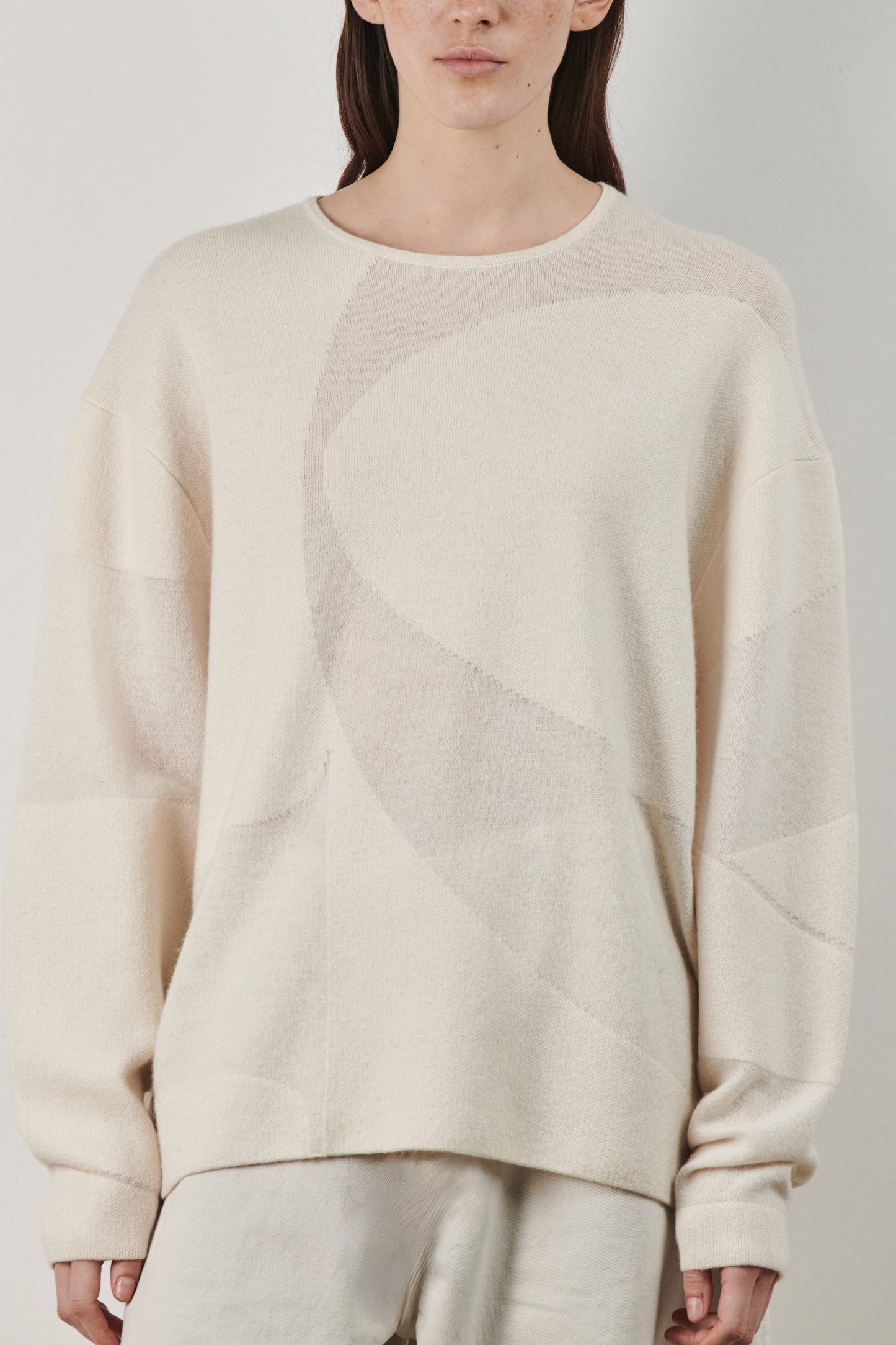 This image features the Arouc Sweater, a stylish and cozy garment ideal for everyday wear. The sweater displays a boxy silhouette and is crafted from a knitted jacquard fabric, presenting a subtle yet sophisticated pattern.