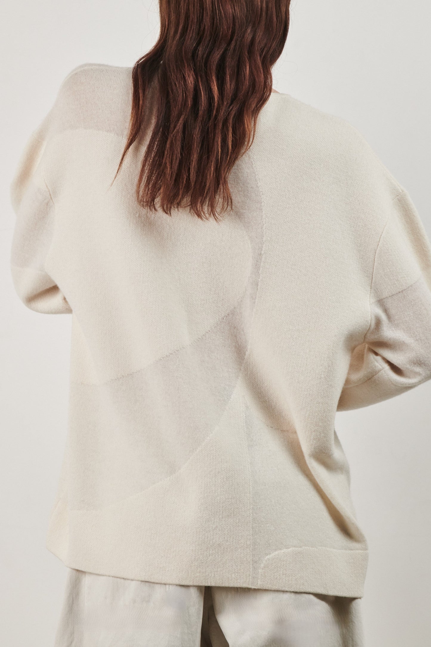 This image features the Arouc Sweater, a stylish and cozy garment ideal for everyday wear. The sweater displays a boxy silhouette and is crafted from a knitted jacquard fabric, presenting a subtle yet sophisticated pattern.