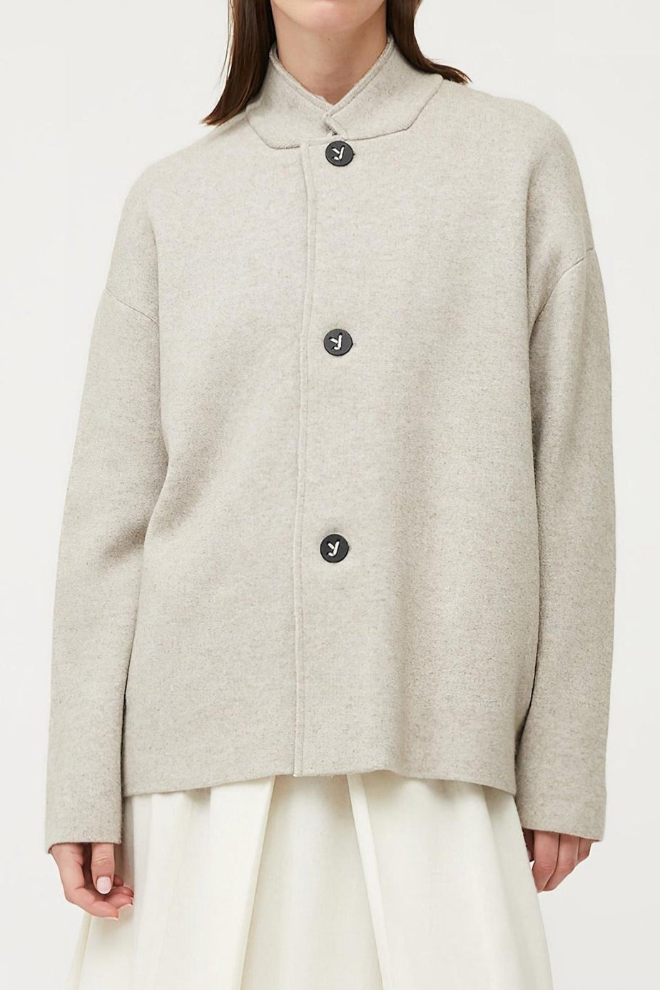 This image features a stylish and practical wind jacket from Oyuna's core collection. The jacket is presented in a relaxed-fit style with a stand-up collar, highlighted by oyuna's signature buttons and welt pockets that enhance its functional appeal.