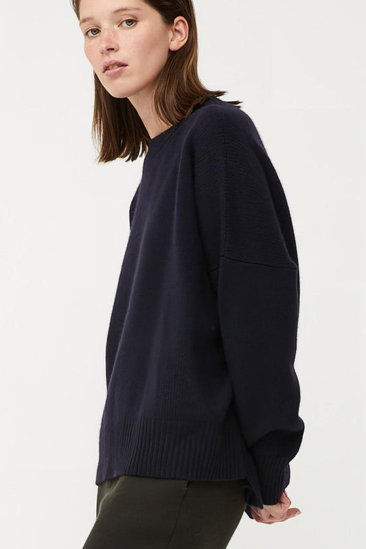 This image features the Aila Sweater, a stylish and versatile garment displayed on a model. The sweater is crafted in a chunky jersey stitch, offering a cozy and comfortable fit.