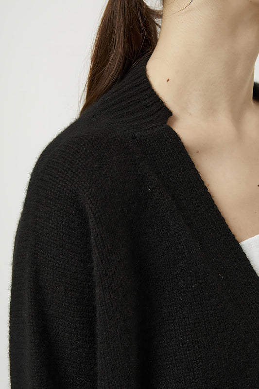 This image features the Aire Cardigan, a luxurious, chunky open cardigan made from pure cashmere. The cardigan is displayed on a model, showcasing its sleek black color and stylish design elements.
