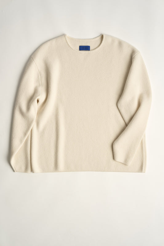 This image features the Axa Sweater, a stylish and comfortable piece that showcases an oversized fit with drop shoulders and sculpted, rounded sleeves. The sweater is knitted using a structured jacquard stitch, which adds texture and depth to its appearance.