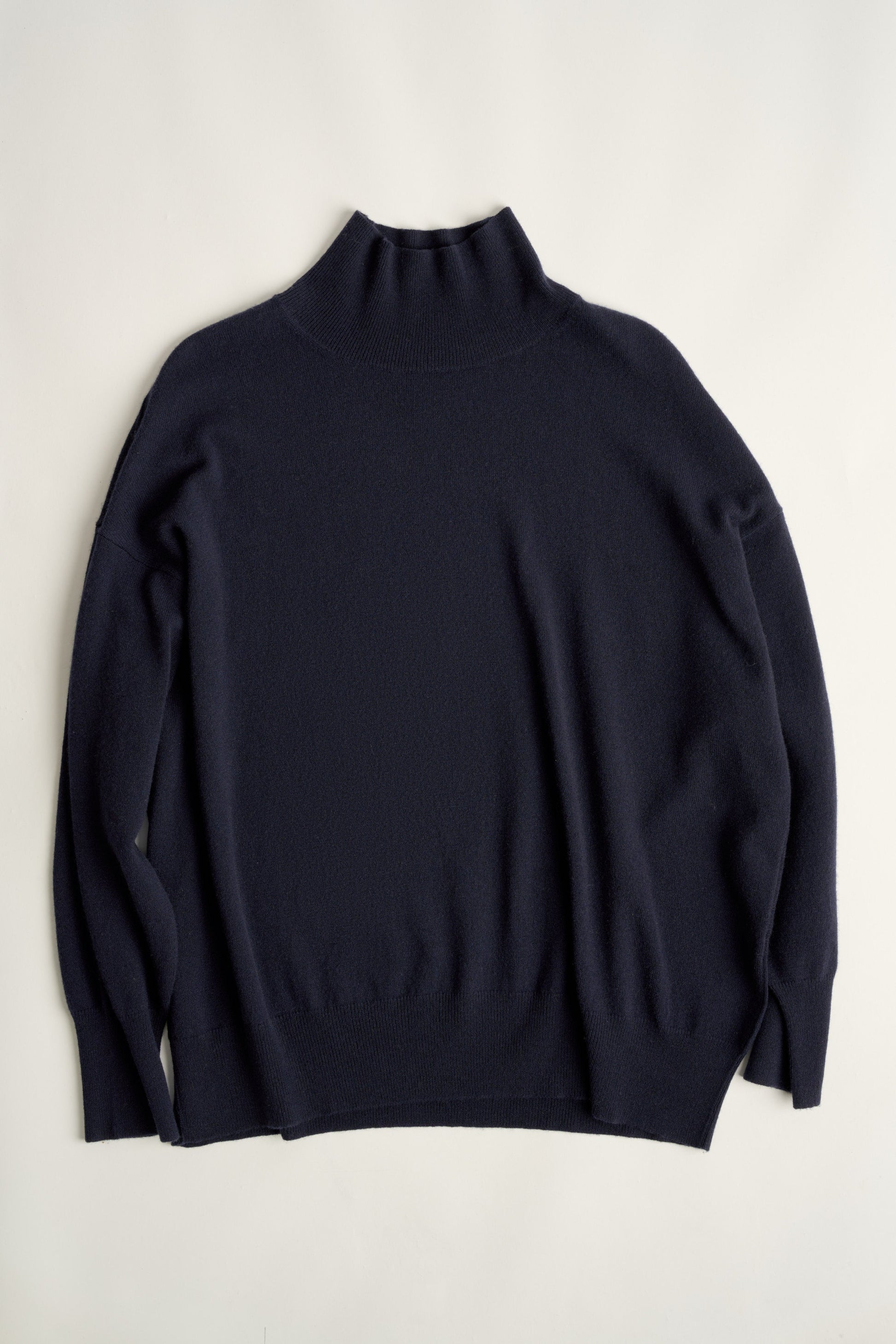 This image features the Kotto Sweater, highlighting its high-neck design and snug, comfortable fit. The sweater is presented in a classic, versatile ocean color, which enhances its elegant and timeless appeal.