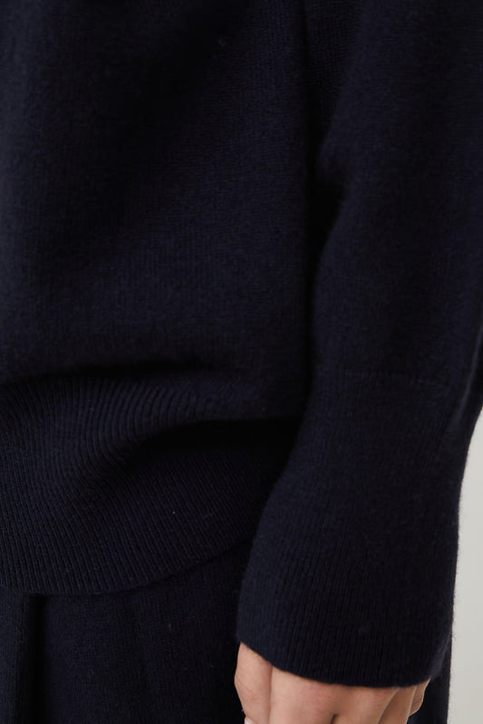 This image features the Kotto Sweater, highlighting its high-neck design and snug, comfortable fit. The sweater is presented in a classic, versatile ocean color, which enhances its elegant and timeless appeal.
