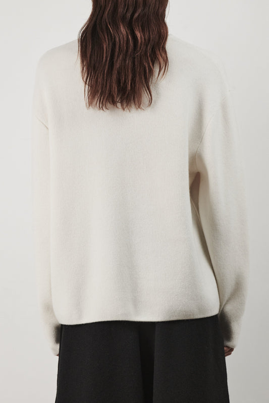 This image features the Axa Sweater, a stylish and comfortable piece that showcases an oversized fit with drop shoulders and sculpted, rounded sleeves. The sweater is knitted using a structured jacquard stitch, which adds texture and depth to its appearance.