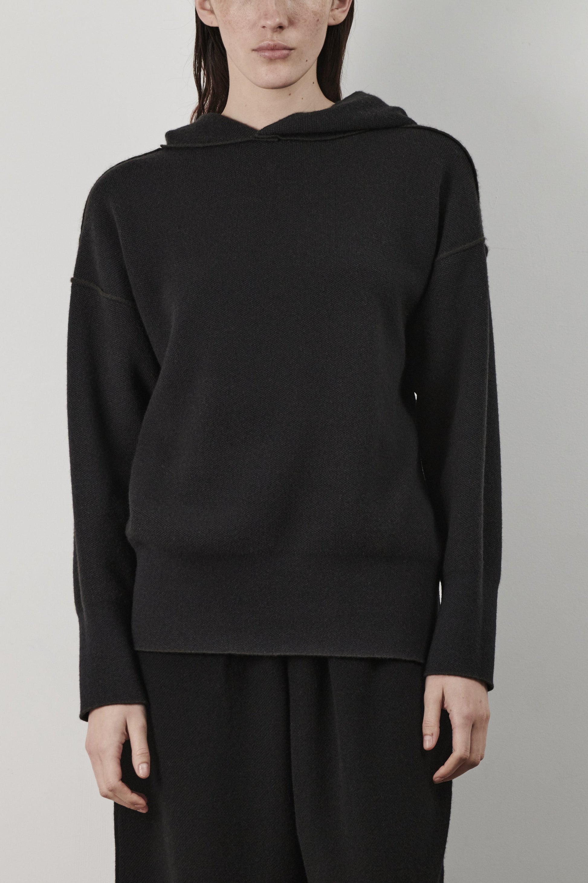 This image features a luxurious forest cashmere hoodie, modeled by a female. The hoodie boasts a modern and minimalist design, with a relaxed fit that enhances its appeal.