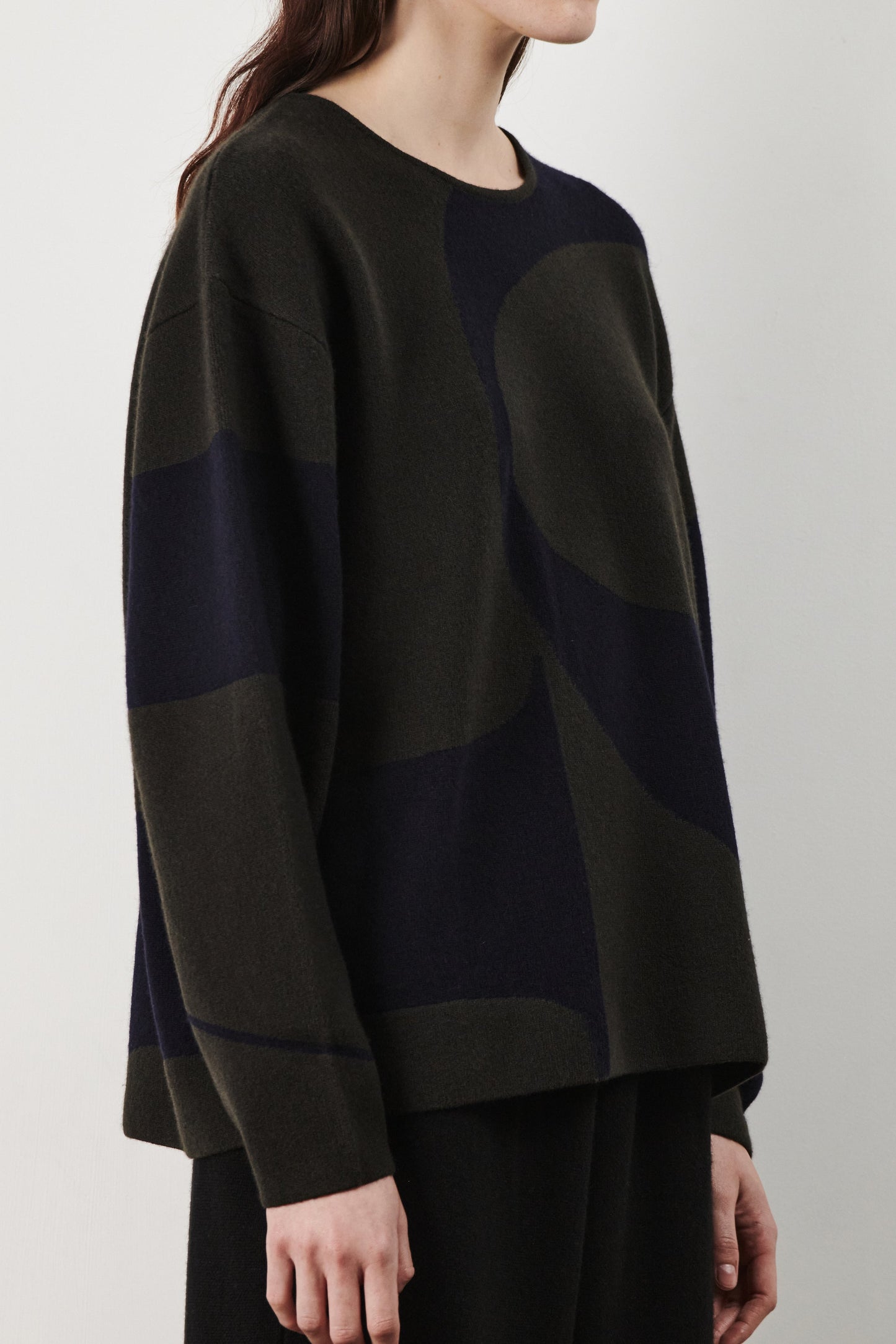 This image features the Arouc Sweater, a stylish and cozy garment ideal for everyday wear. The sweater displays a boxy silhouette and is crafted from a knitted jacquard fabric, presenting a subtle yet sophisticated pattern.