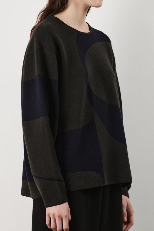 This image features the Arouc Sweater, a stylish and cozy garment ideal for everyday wear. The sweater displays a boxy silhouette and is crafted from a knitted jacquard fabric, presenting a subtle yet sophisticated pattern.