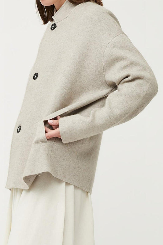 This image features a stylish and practical wind jacket from Oyuna's core collection. The jacket is presented in a relaxed-fit style with a stand-up collar, highlighted by oyuna's signature buttons and welt pockets that enhance its functional appeal.